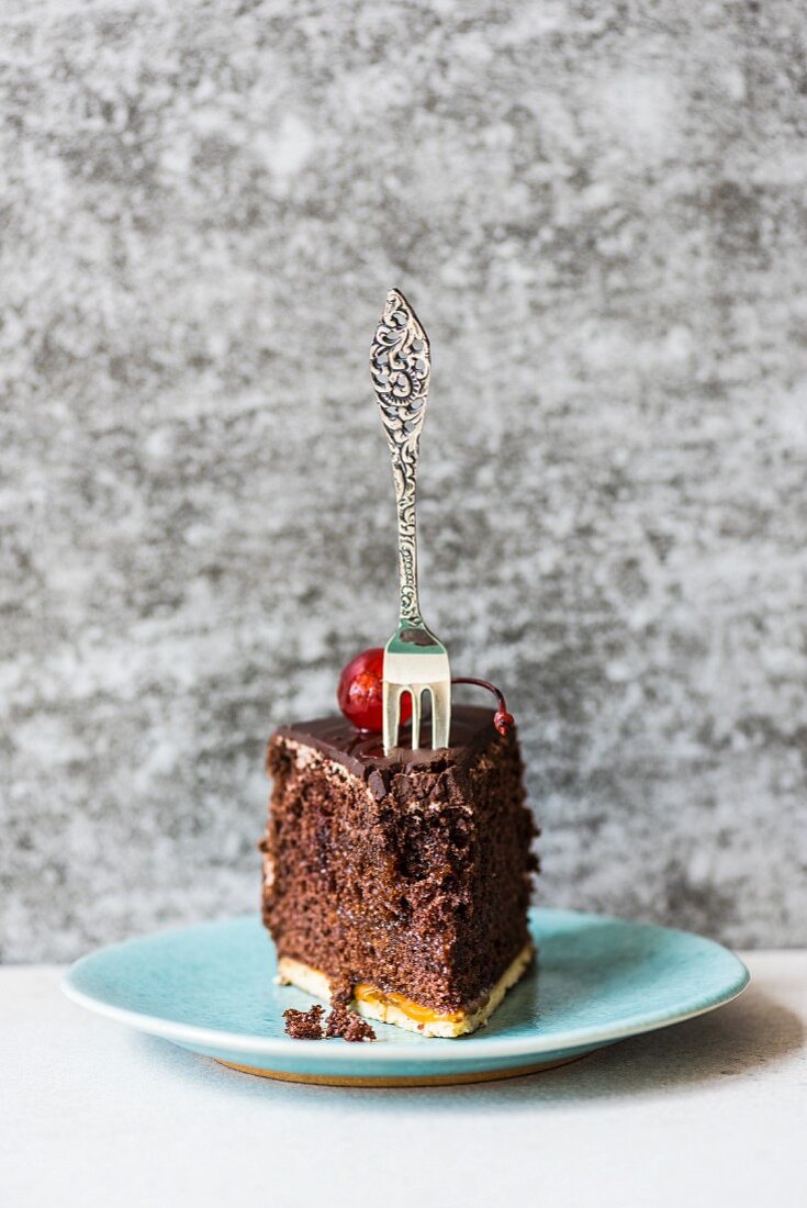 A piece of chocolate with a cocktail and a fork on a plate