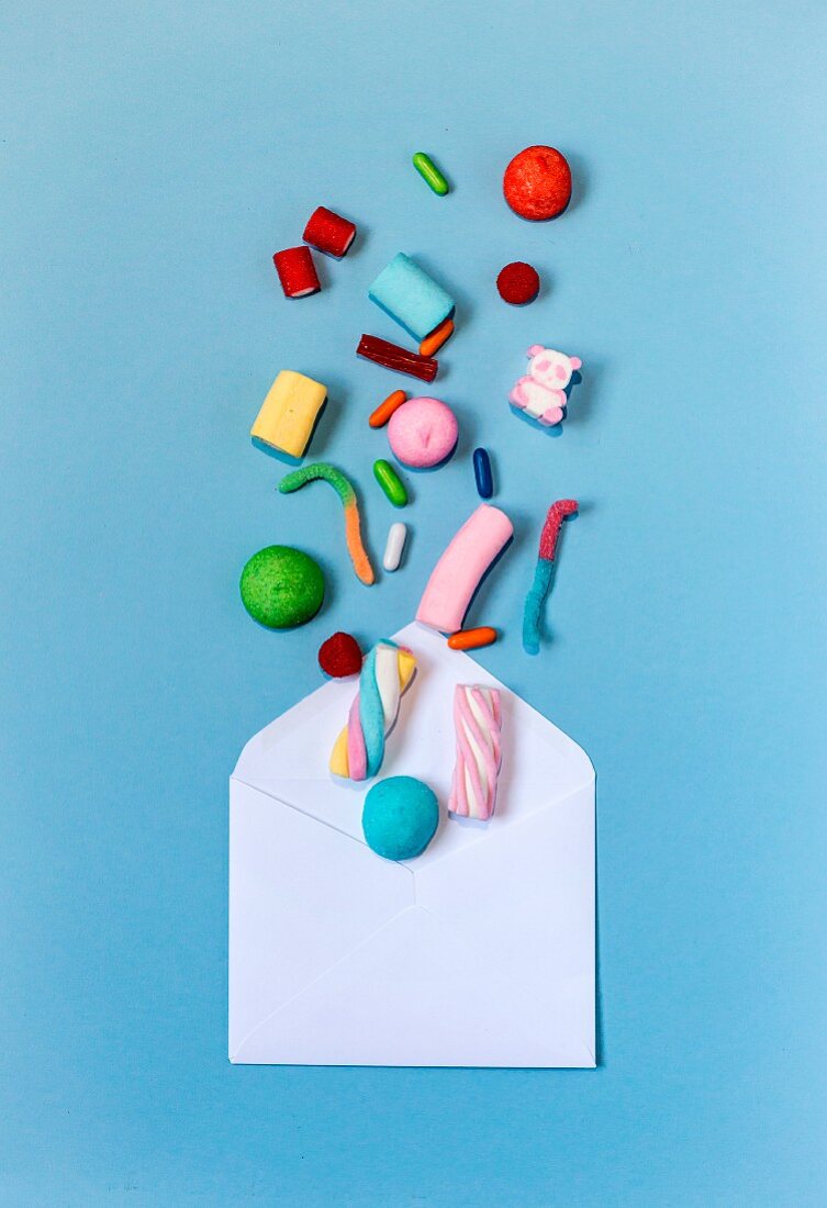 Colourful sweets coming out of an envelope on a light-blue background