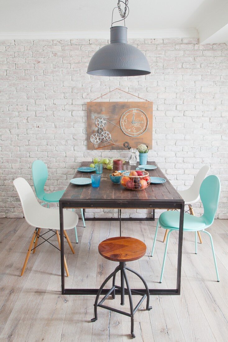 Klassiker Stühle um Tisch und DIY-Kunstobjekt mit Zahnrädern als Wanddekoration