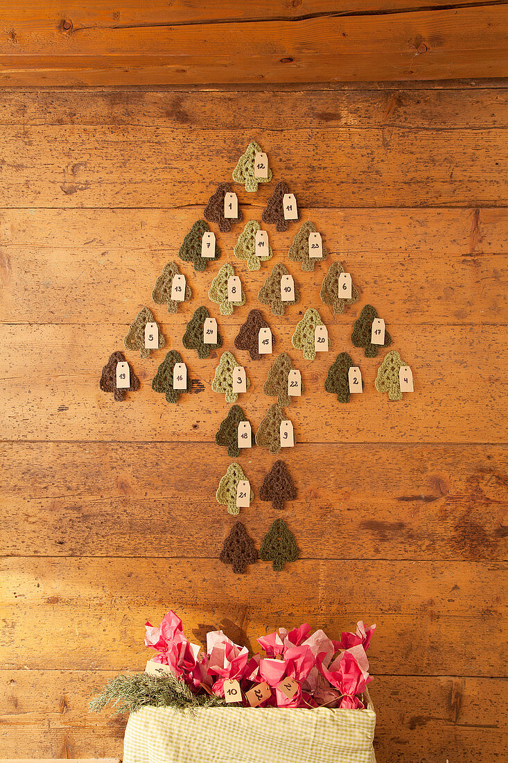 Advent calender made from crocheted fir trees on wooden wall