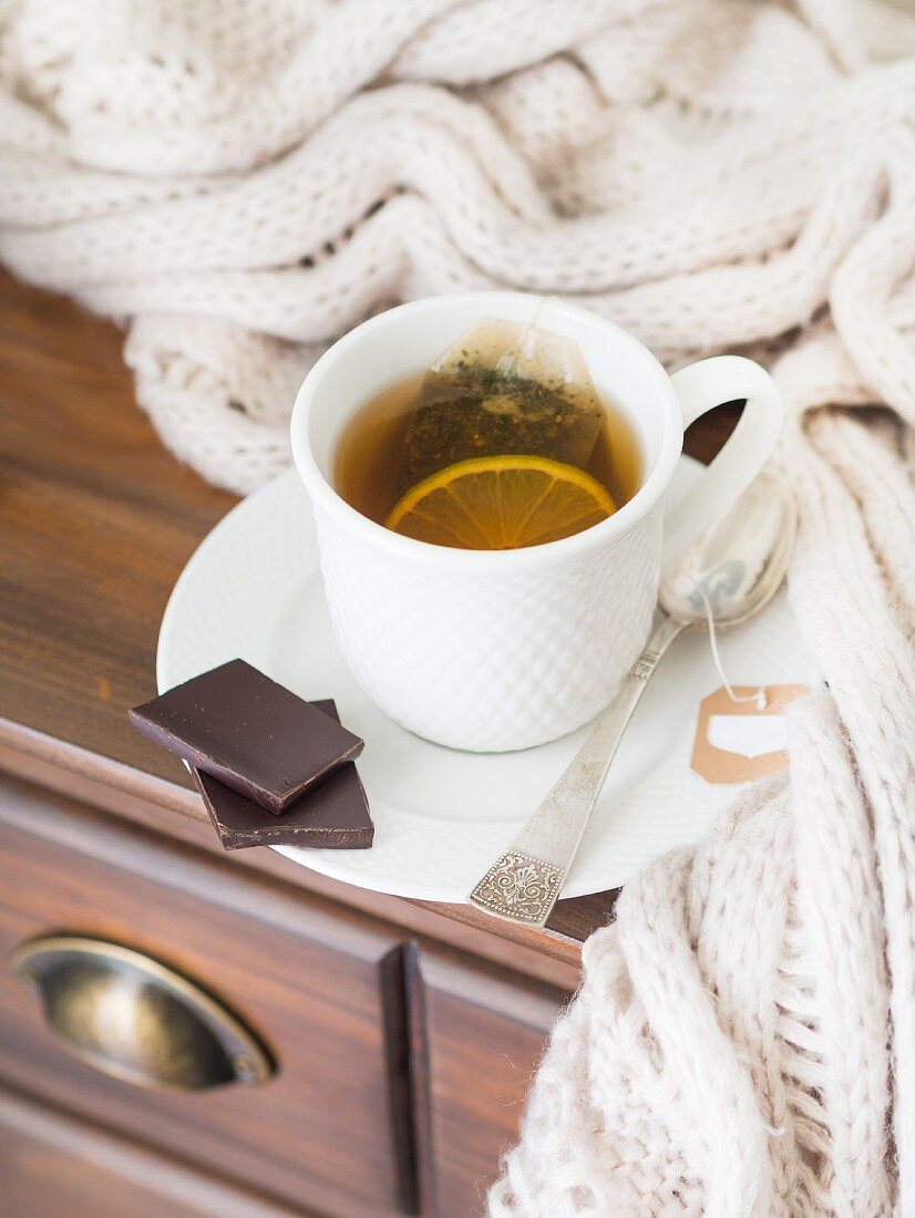 A cup of hot tea with lemon, served with dark chocolate