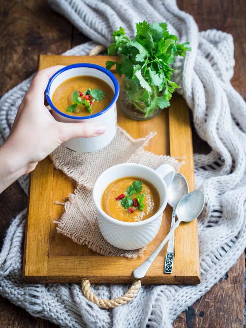 Vegan vegetable cream soup in two cups on a wooden background.