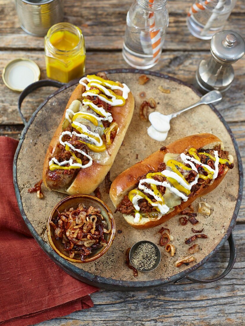 Chili Hot Dogs, garniert mit gebratenen Zwiebeln, Senf und Mayonnaise