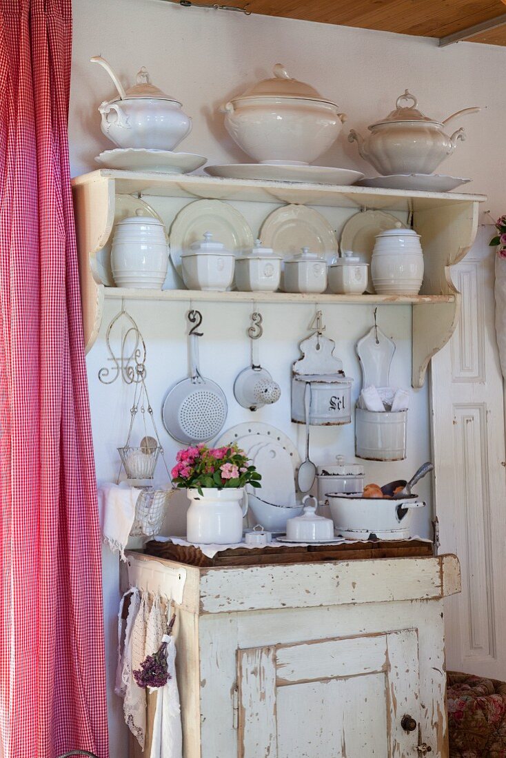 White crockery on wall-mounted shelves and kitchen utensils on old cabinet