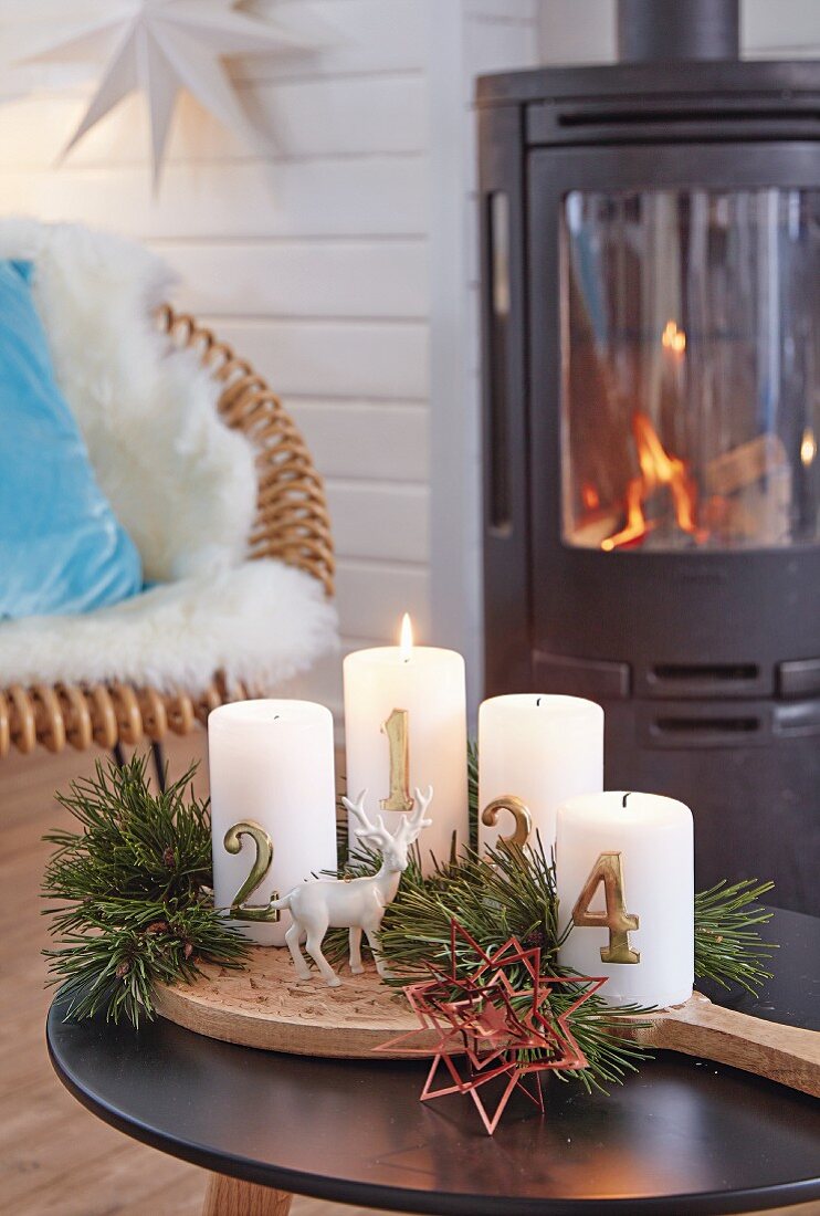 Advent candles with pine sprigs on a wooden board in front of a wood-burning kiln