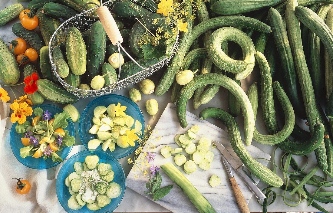 Three different cucumber salads in bowls beside ingredients