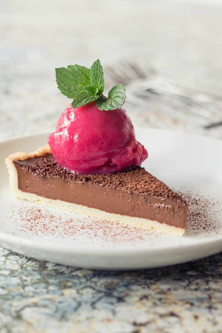 A slice of chocolate tart with raspberry sorbet