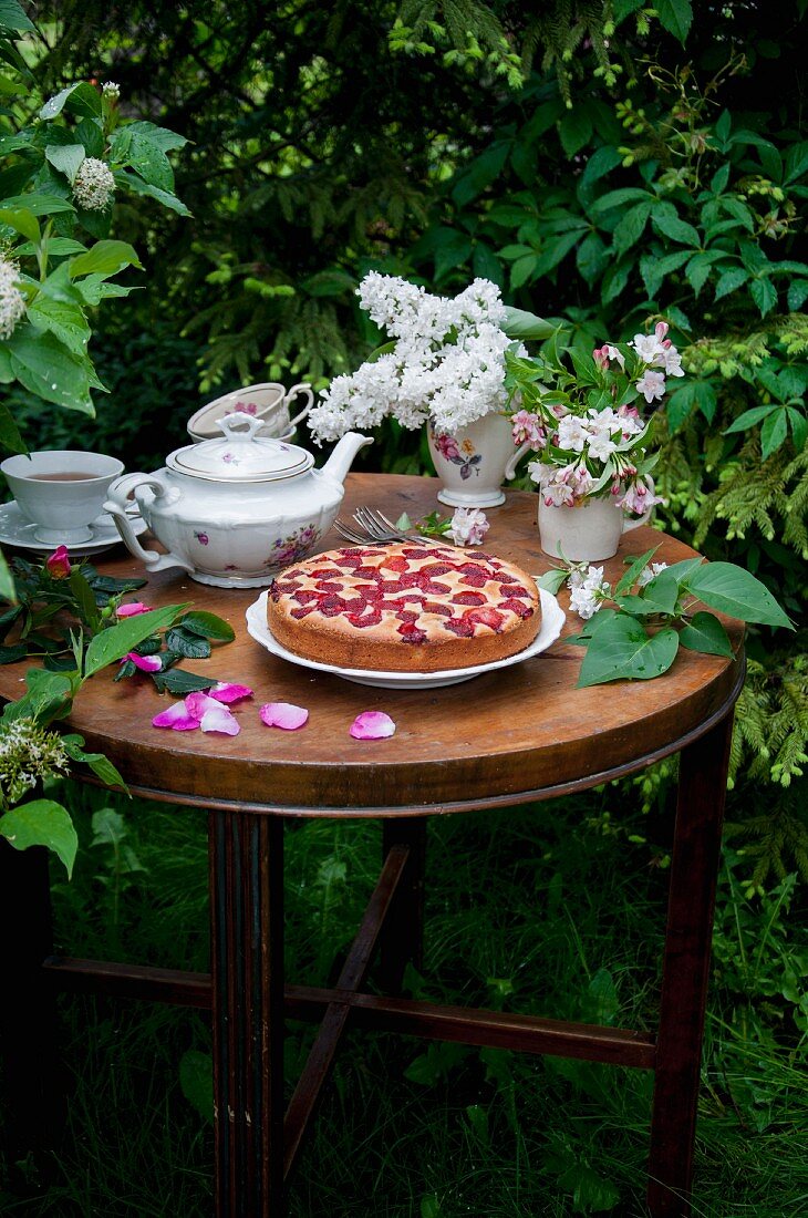 Einfacher Erdbeerkuchen und Tee auf Gartentisch