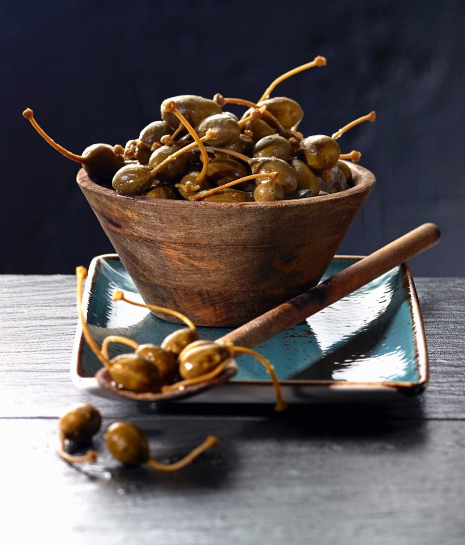 Giant capers in a wooden bowl and on a wooden spoon