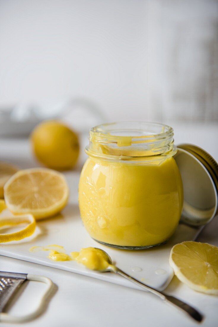 Lemon curd in a jar with fresh lemons