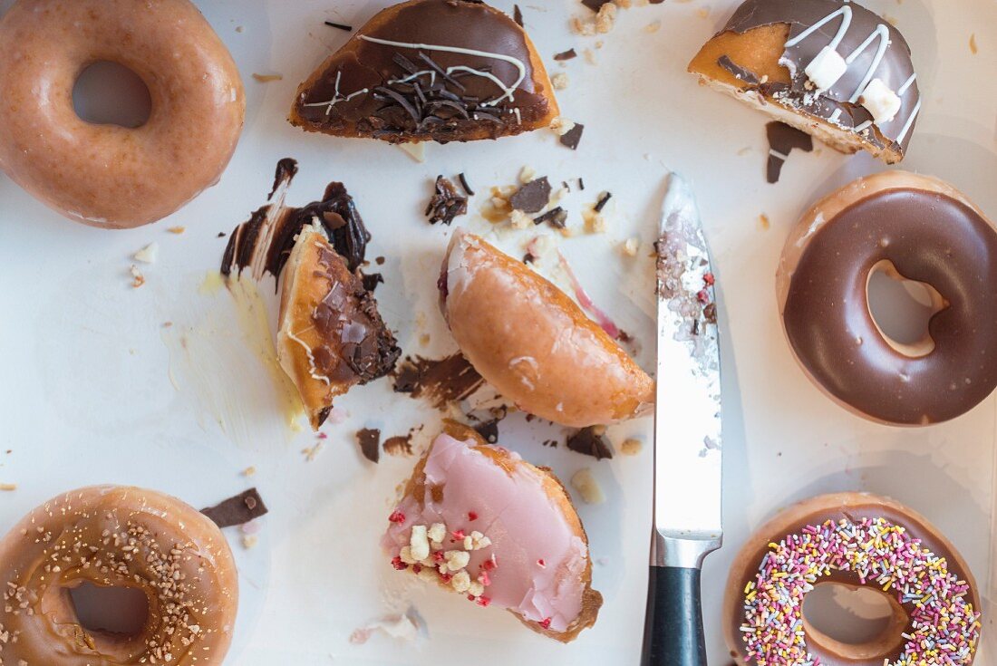 A box of half eaten donuts with a knife