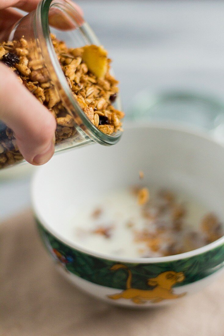 Granola being poured into a bowl of milk