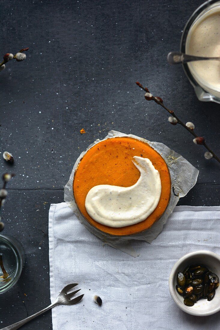 A vegan pumpkin cake with cashew cream and caramelised pumpkin seeds