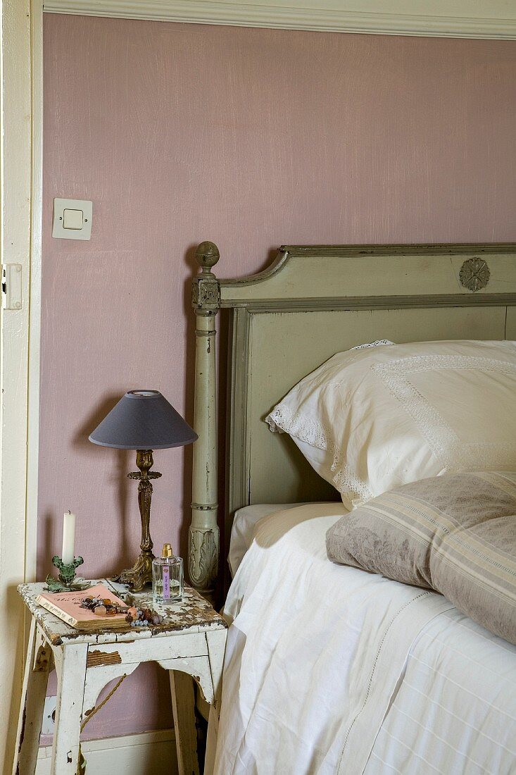 Shabby-chic wooden stool used as bedside table next to bed with wooden headboard