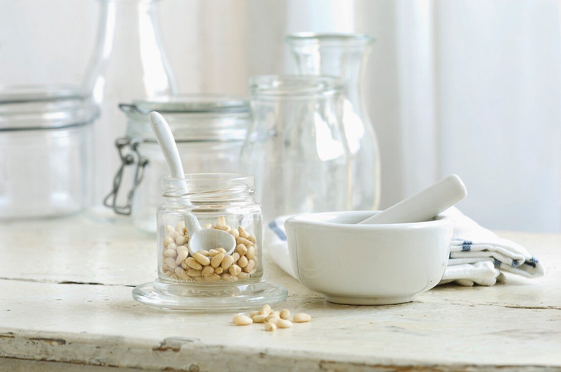 Pine nuts in a glass and mortar on a rustic kitchen table