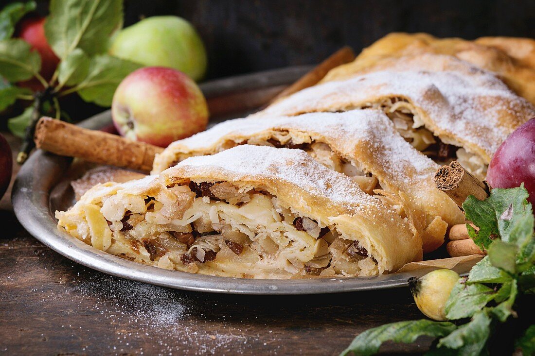 Close up of sliced homemade apple strudel with sugar powder on vintage metal tray