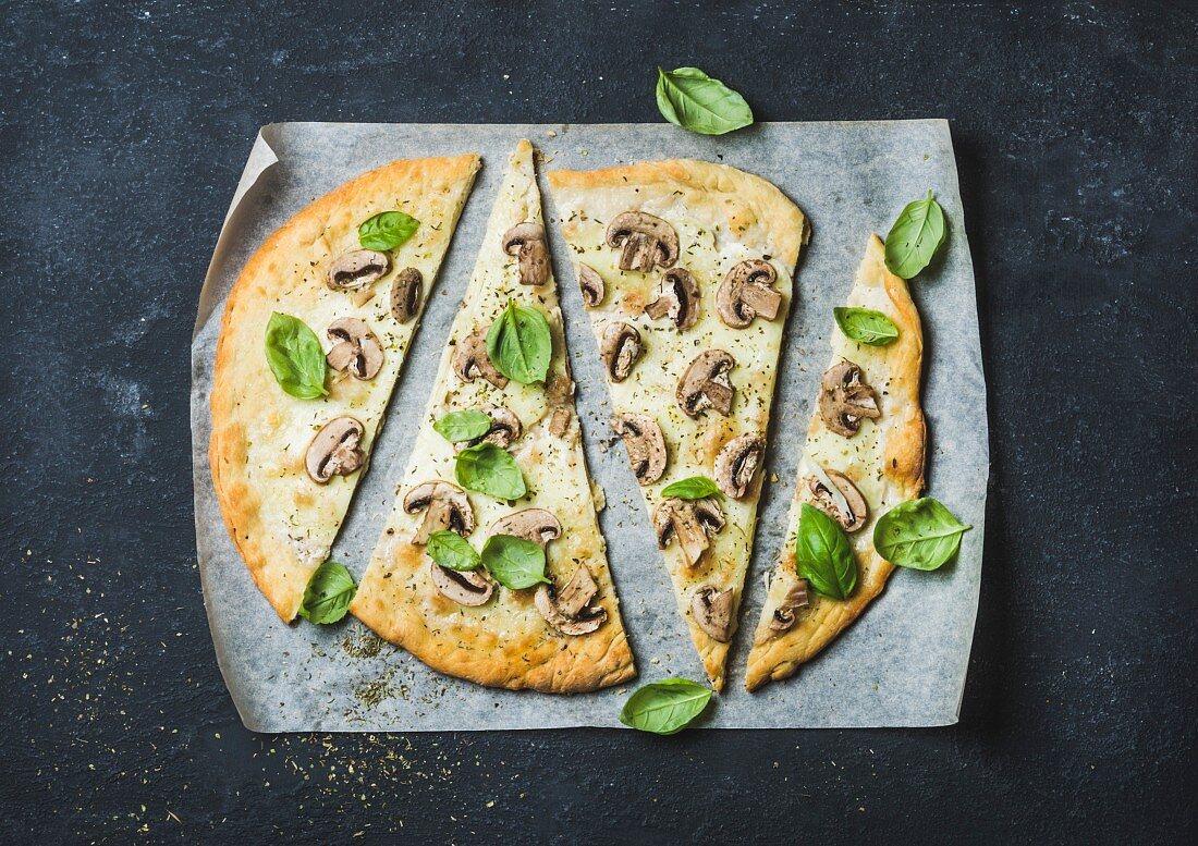 Pizza mit Pilzen und Basilikum in Scheiben geschnitten