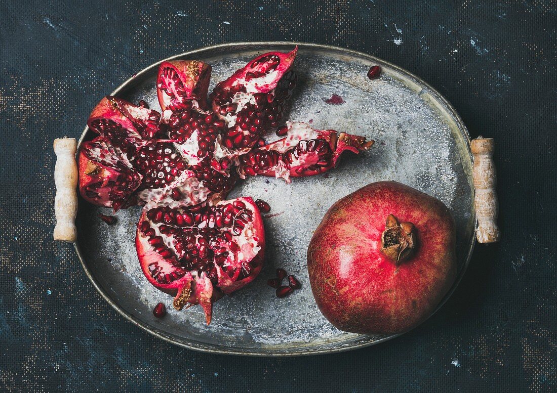 Fresh ripe pomegranate broken in pieces in vintage metal tray