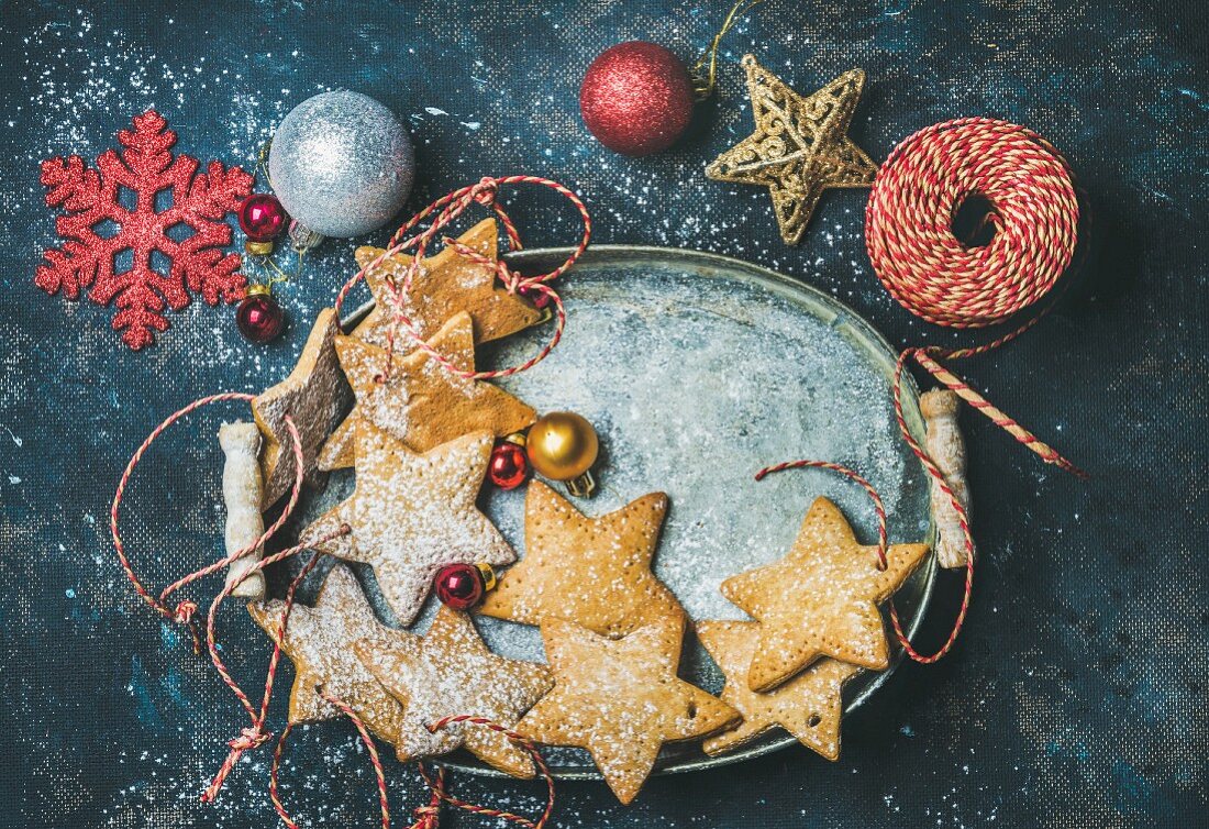 Lebkuchensterne als Christbaumschmuck, dekorative Schneeflocken und Baumkugeln in Metallschale