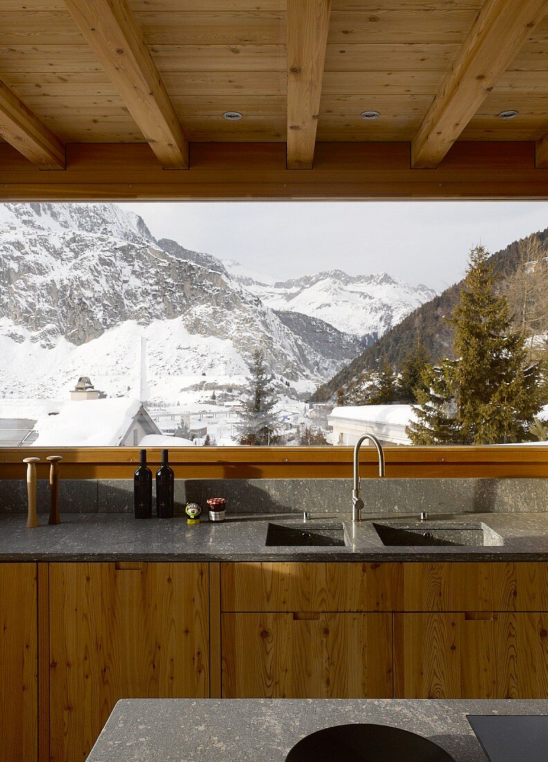 Kitchen in modern wooden house with view of wintry landscape