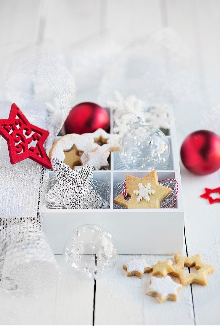 Box with christmas biscuits and decorations on white table