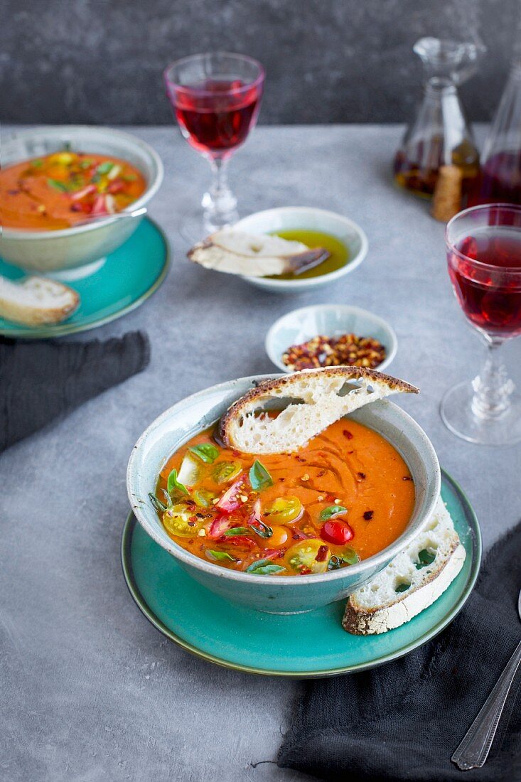 Suppe aus gebratenen Tomaten, garniert mit Kirschtomaten und Basilikum