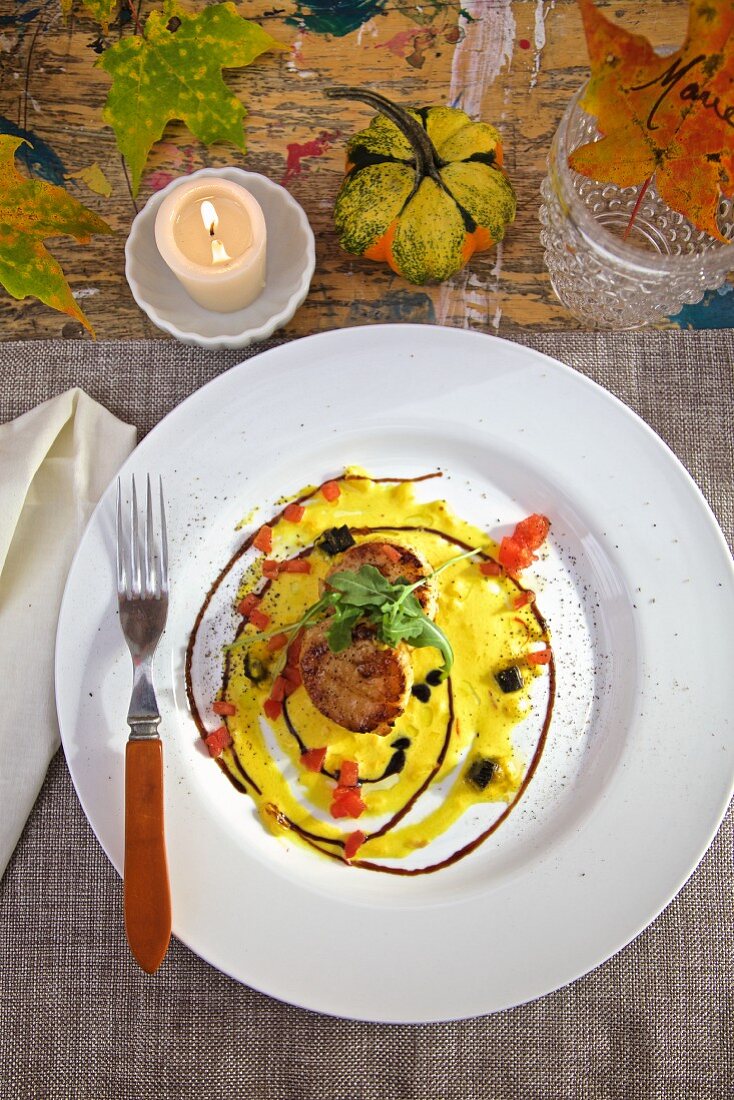 Jakobsmuscheln mit Safransauce und Trüffeln auf herbstlich gedecktem Tisch