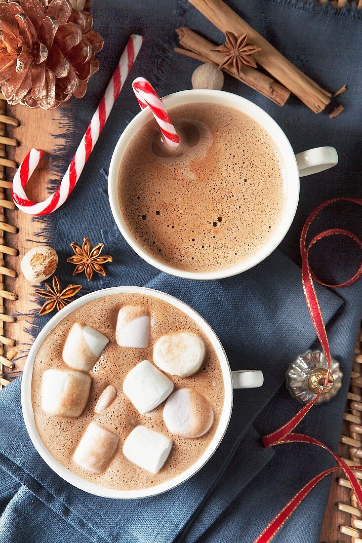 Two big cups of hot chocolate with a candy cane and marshmallows for Christmas