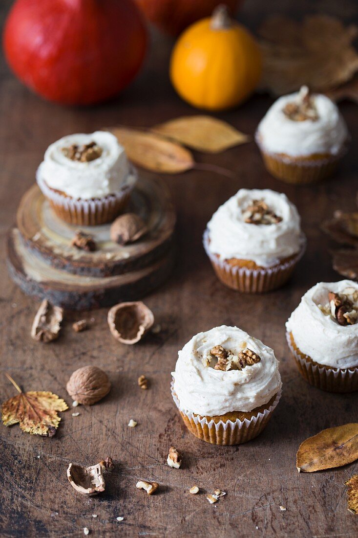 Pumpkin cupcakes with cream cheese frosting and walnuts.