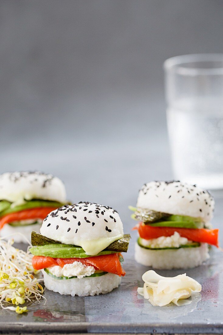 Three sushi burgers with smoked salmon, cucumber, fresh cheese, wasabi, nori and avocado