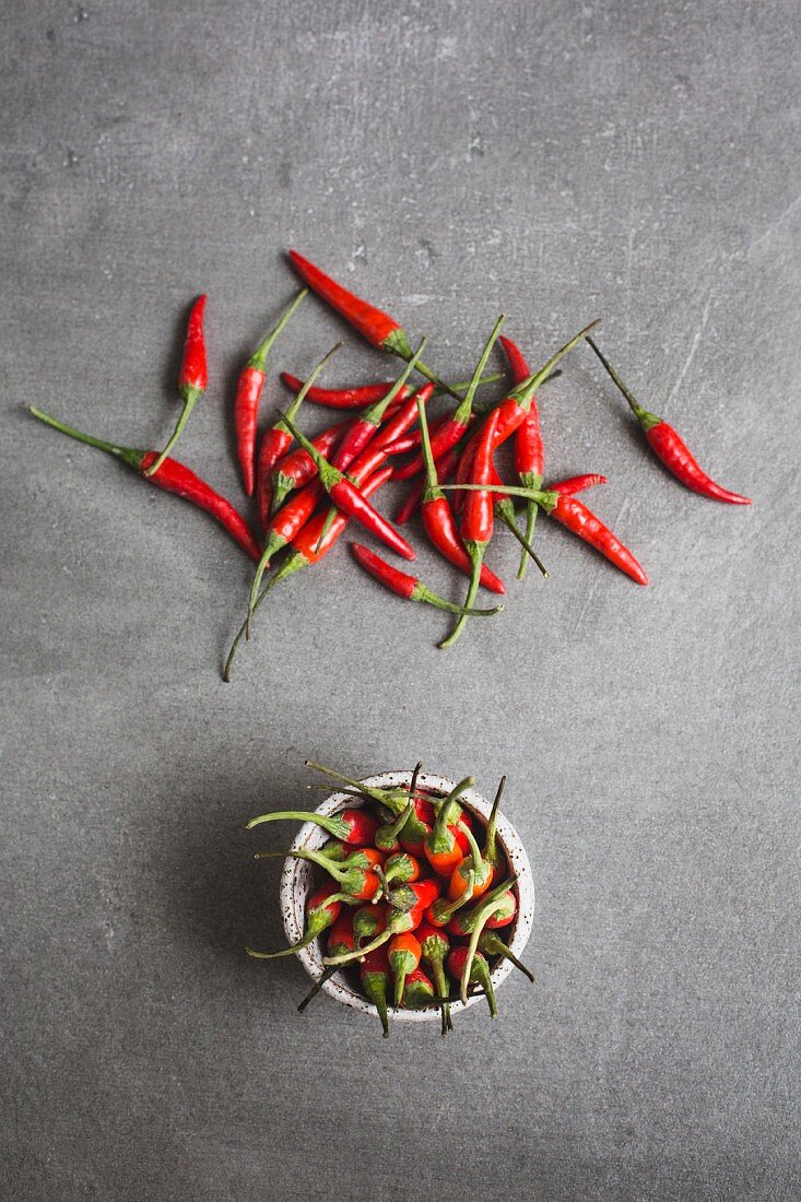 A bowl of chillis and scattered chillis (seen from above)