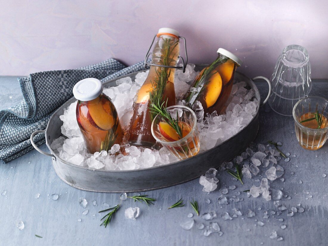 Peach iced tea with rosemary in bottles and glasses