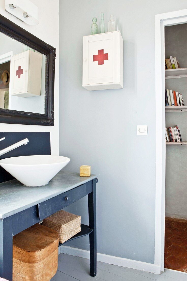 Countertop sink on washstand with drawer next to medicine cabinet on wall