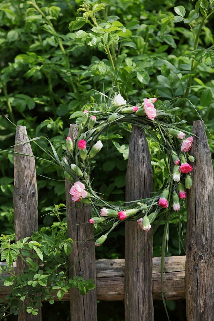 Wreath of carnations hung on wooden fence