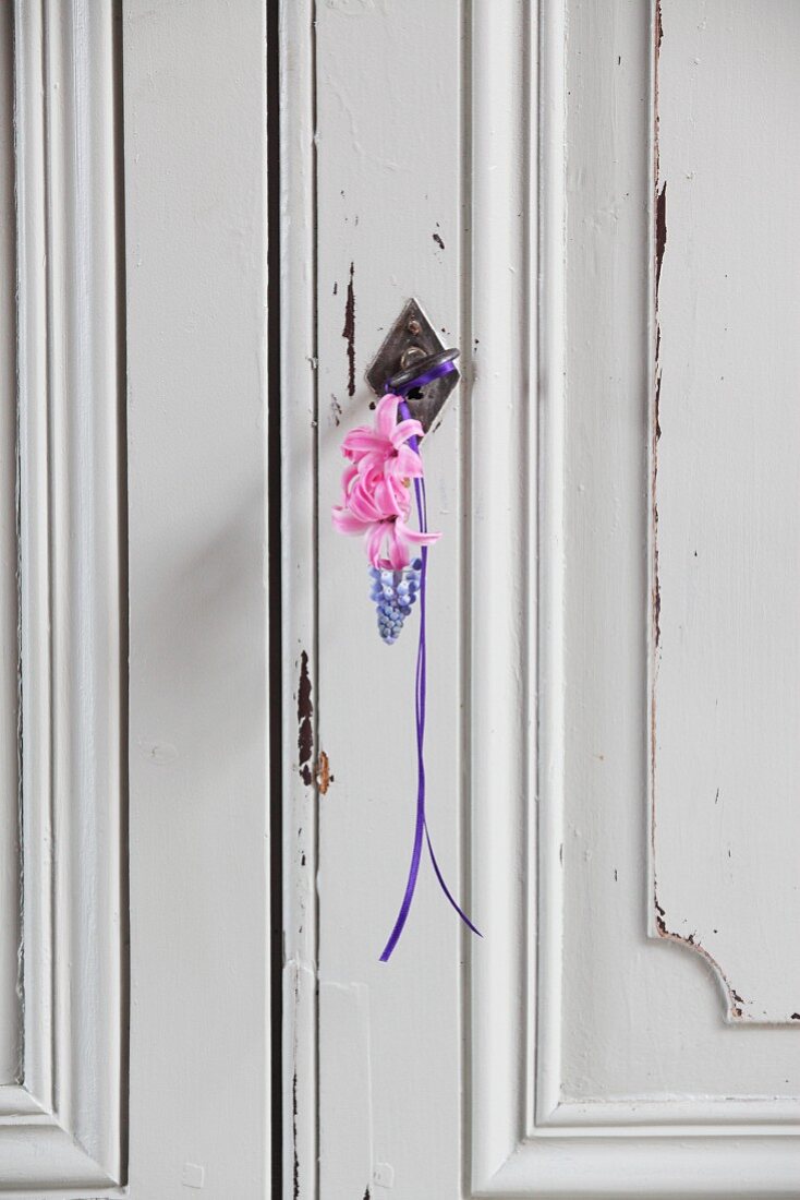 Grape hyacinth and two pink hyacinth florets hung from wardrobe key