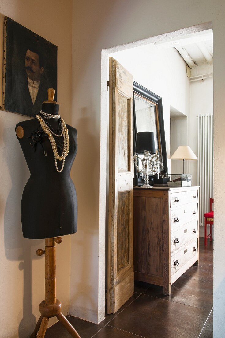 Tailors' dummy draped with necklaces outside bedroom door