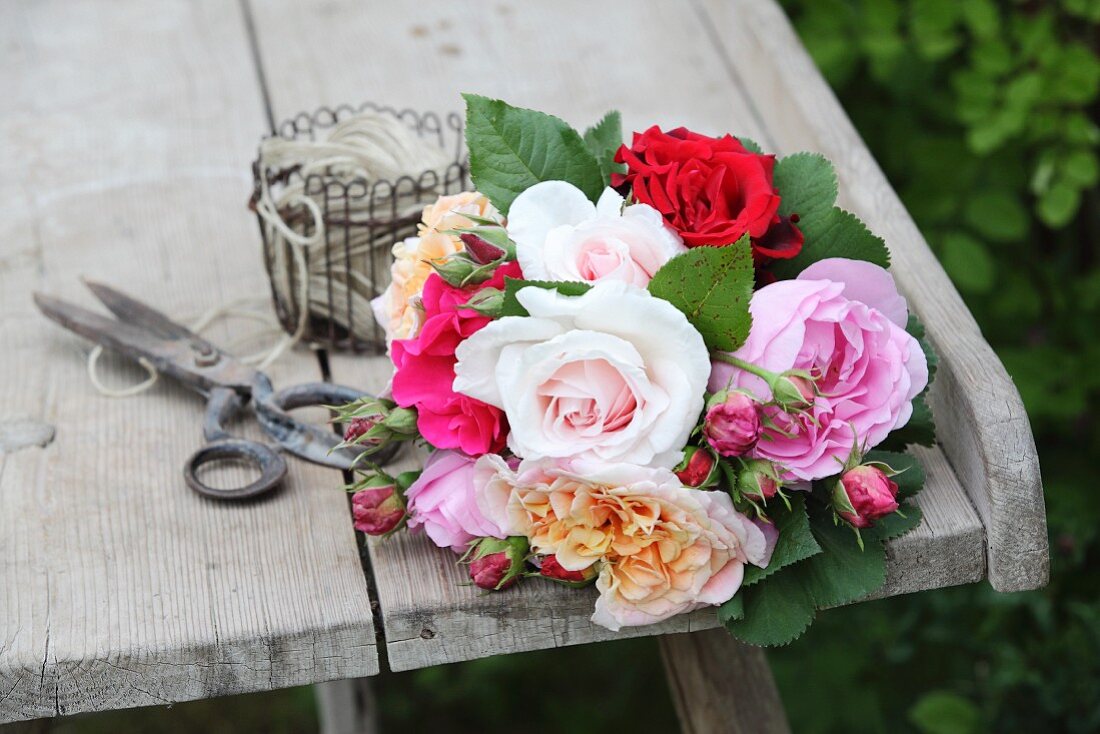 Bouquet of roses in various colours on weathered wooden table