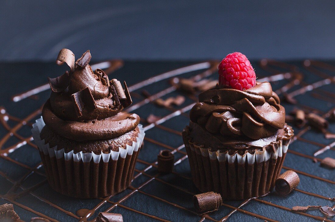 Decadent chocolate cupcakes with chocolate icing, shavings of chocolate and a raspberry