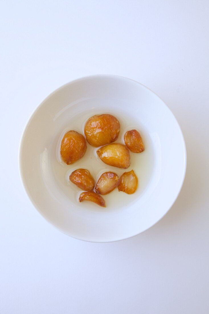 Roasted Garlic in olive oil on a white plate