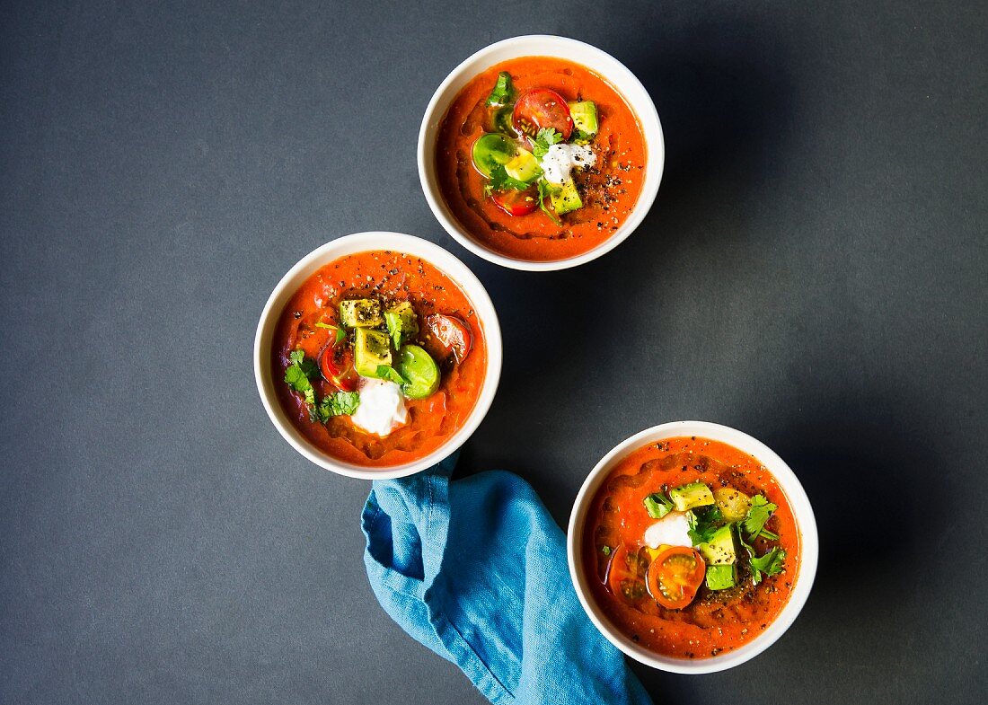 Chilled heirloom tomato gazpacho soup topped with avocado, cherry tomatoes, cilantro and a dallop of sour cream