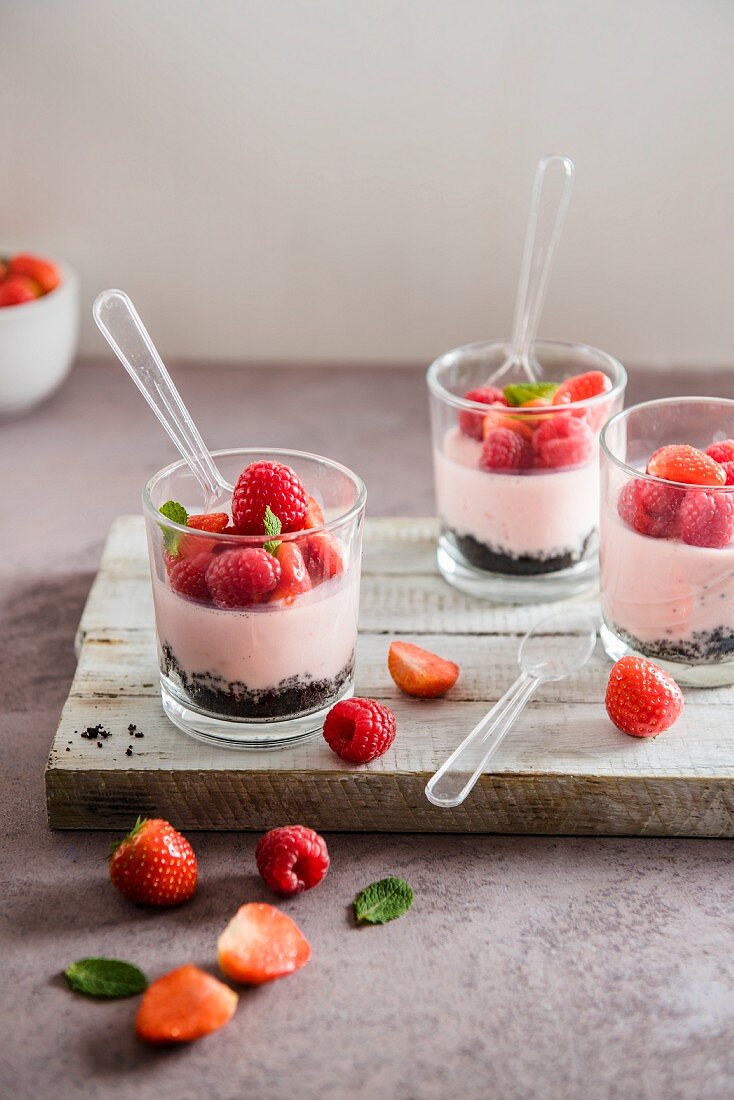 Kleine Himbeer-Joghurt-Käsekuchen mit frischen Himbeeren und Erdbeeren im Glas