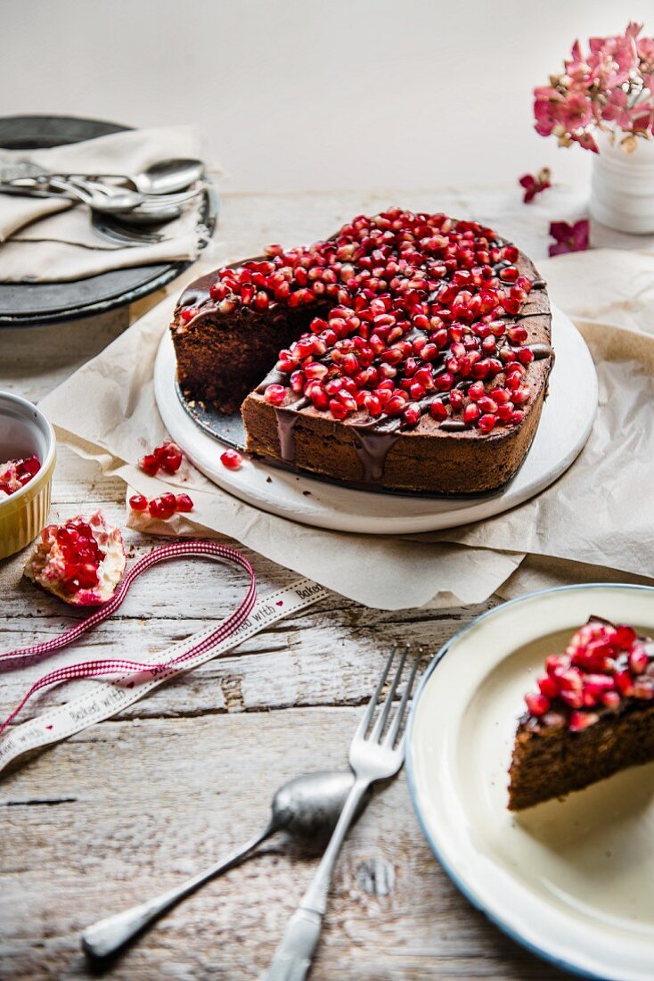 Chocolate cake in a shape of a heart with chocolate glaze and pomegranate seeds