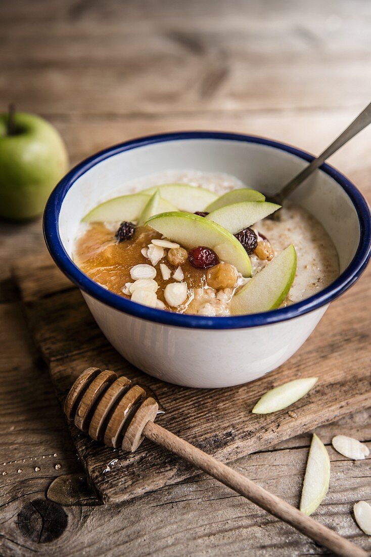 A bowl of porridge with apple puree, sultanas, almond, honey and apple slices
