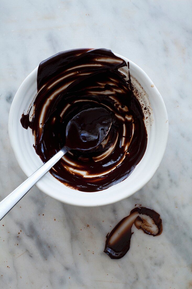 Geschmolzene dunkle Schokolade in Rührschüssel mit Löffel