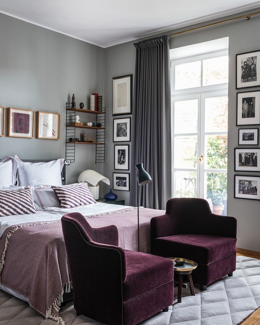 Zwei violette Samtsessel vor dem Bett im glamourösen Schlafzimmer