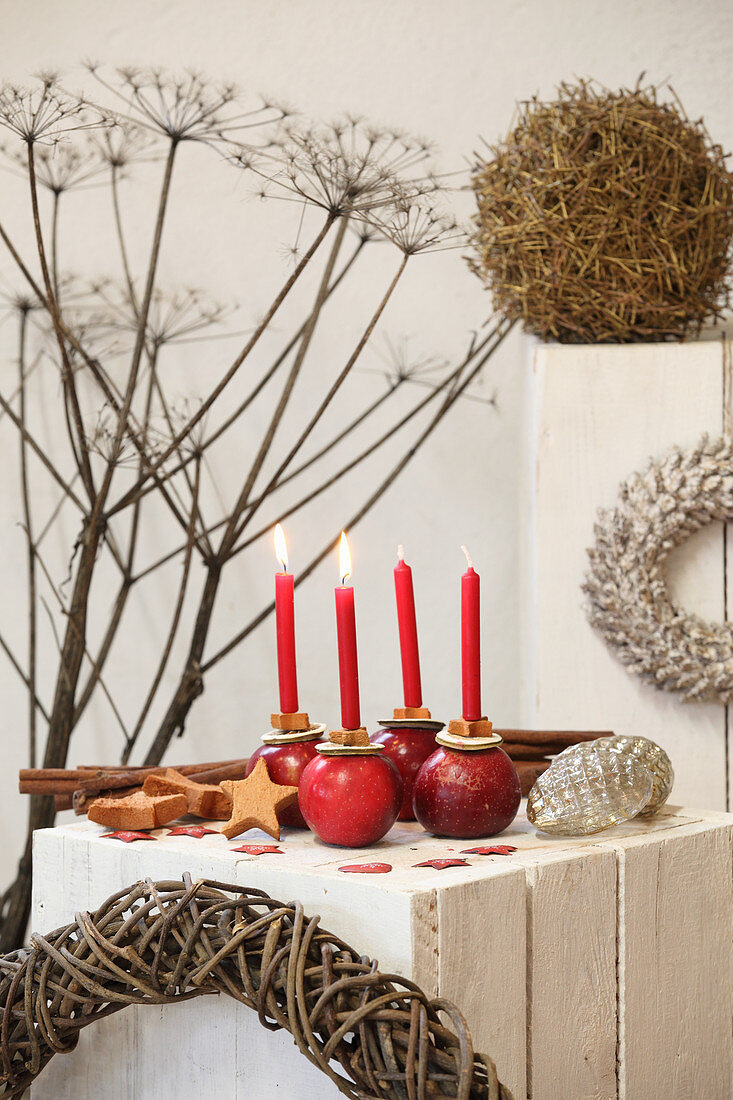 Four red candles in apples on white wooden block