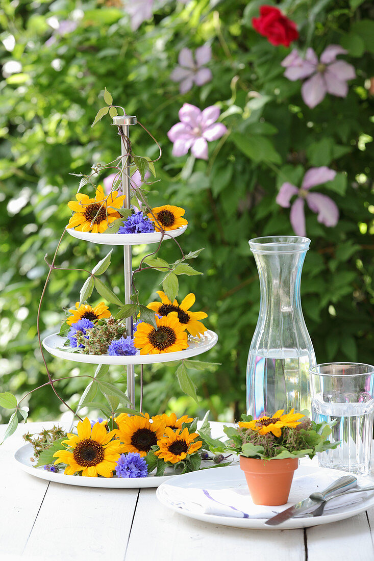 Etagere verziert mit Blüten von Sonnenblumen und Kornblumen