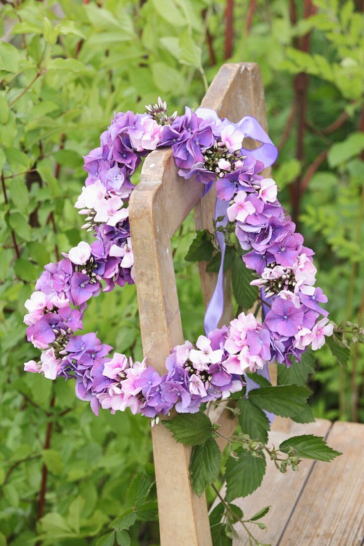 Heart-shaped wreath of hydrangea and phlox flowers on old wooden chair
