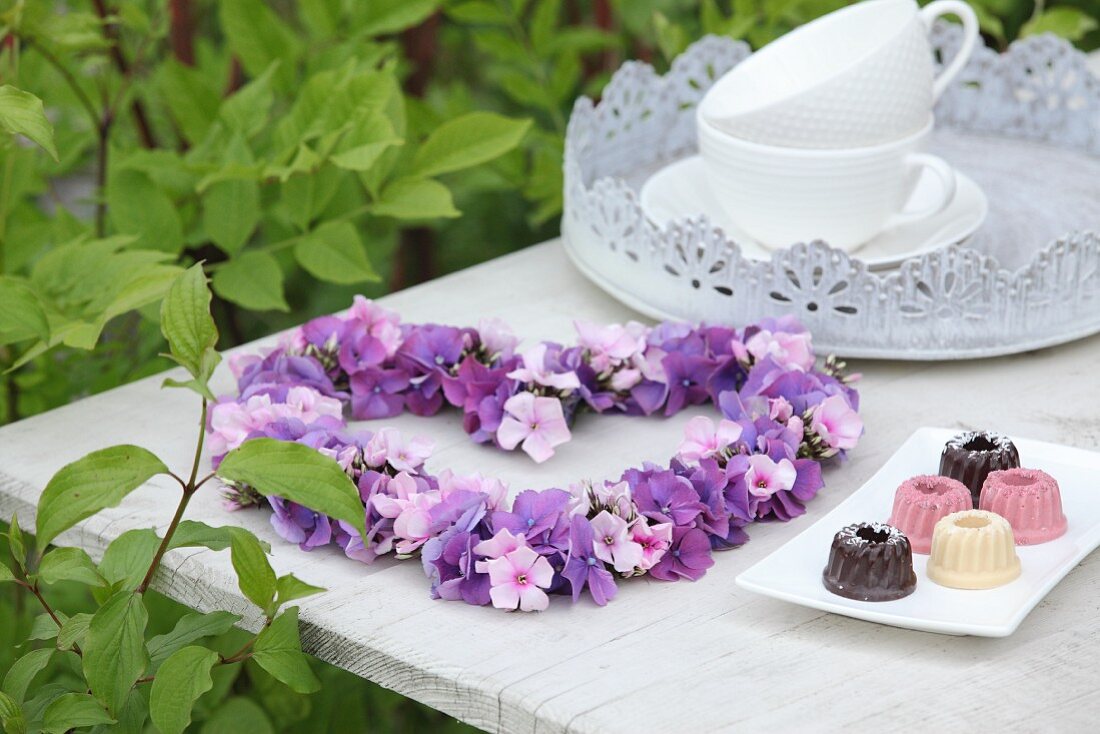 Herz aus Hortensienblüten und Phlox auf dem Tisch im Garten