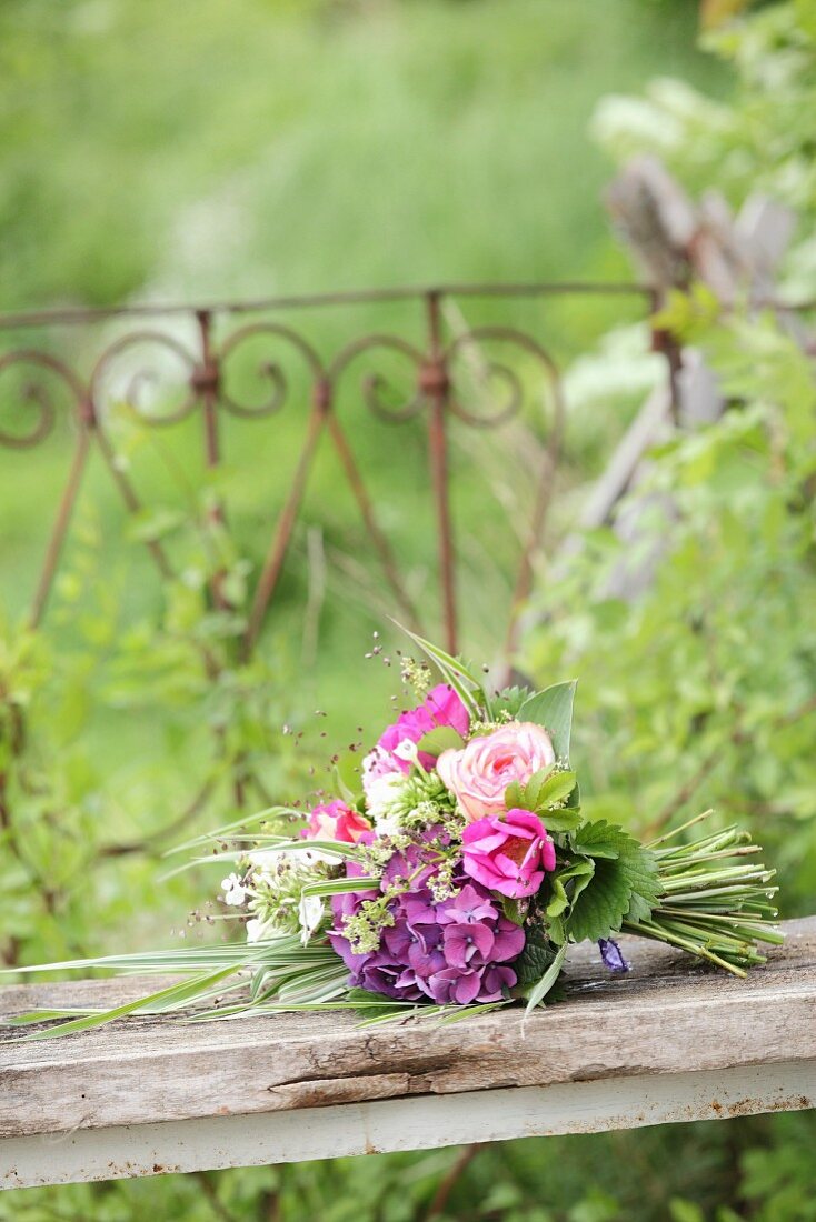 Luxuriant summer bouquet of pink flowers on wooden board